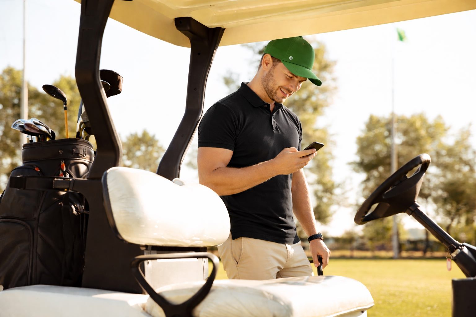 Golfer beside a cart checking the app during the round